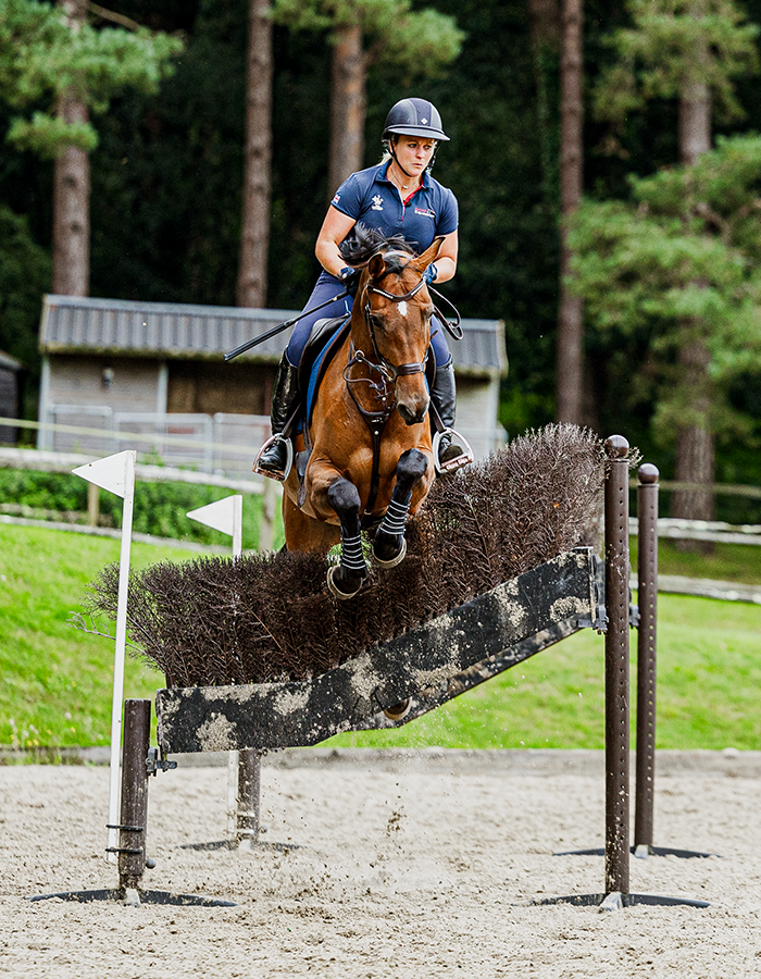 weatherbeeta sponsored rider gemma stevens jumping a horse over a cross country type fence