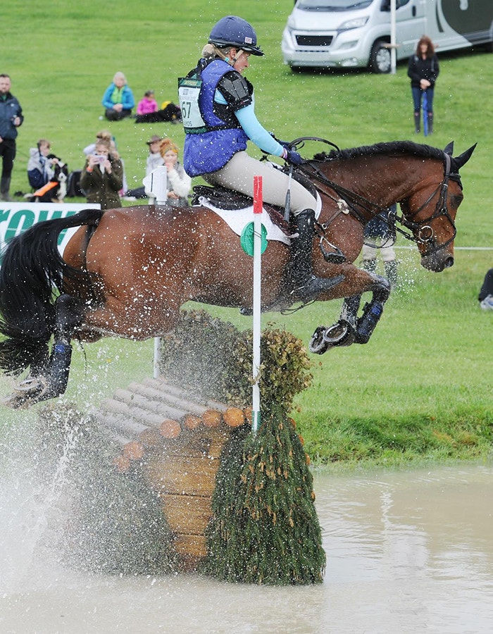 weatherbeeta sponsored rider jodie amos jumping a horse over a cross country fence in water