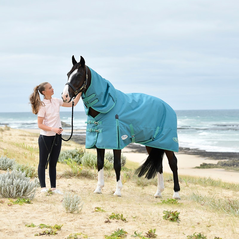 Girl and horse standing on beach wearing WeatherBeeta Green-Tec horse rug